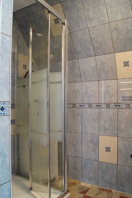 La salle d'eau de l'étage, faite de carrelage bleu, contient une douche et une vasque.