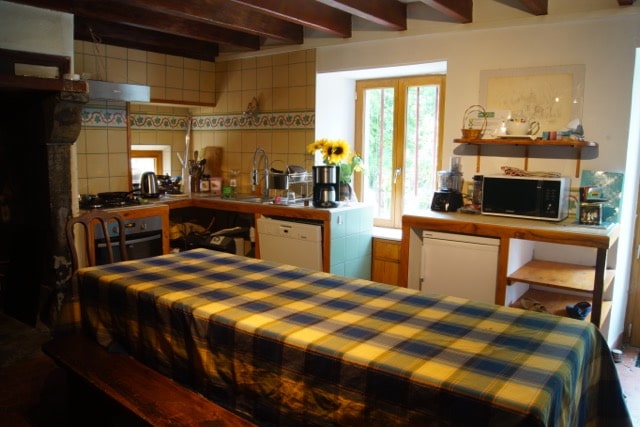 La salle-à-manger se constitue d'une grande table avec deux grands bancs qui la longe. Derrière, la cuisine, toute équipée.