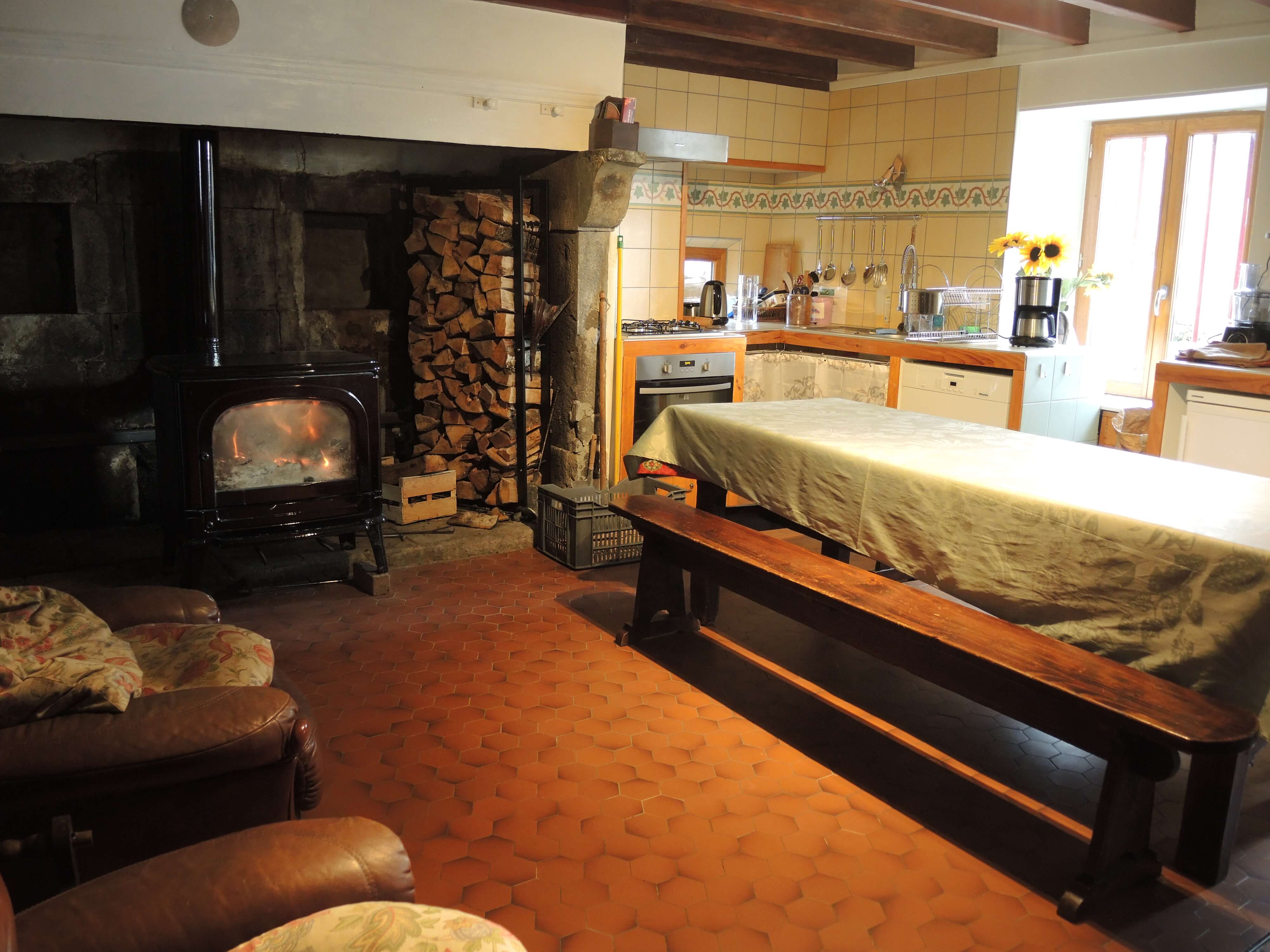 En plus des deux fauteuils et de la table à manger, on peut voir le poêle allumé, avec des morceaux de bois à l'arrière, pour alimenter le feu.